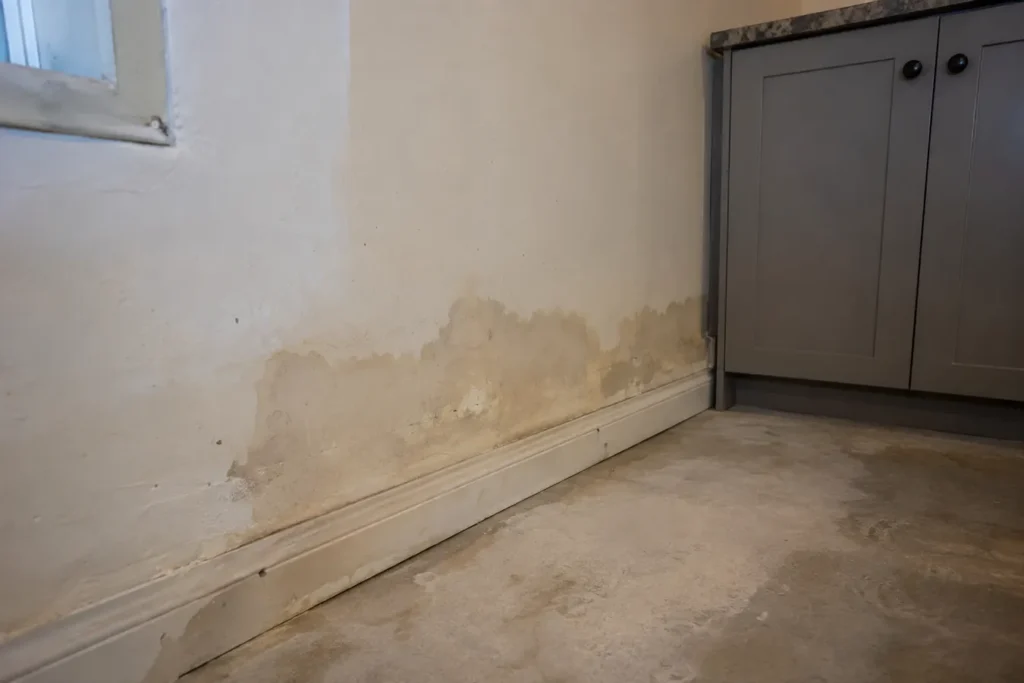 Waterstained lower drywall section near basement cabinet